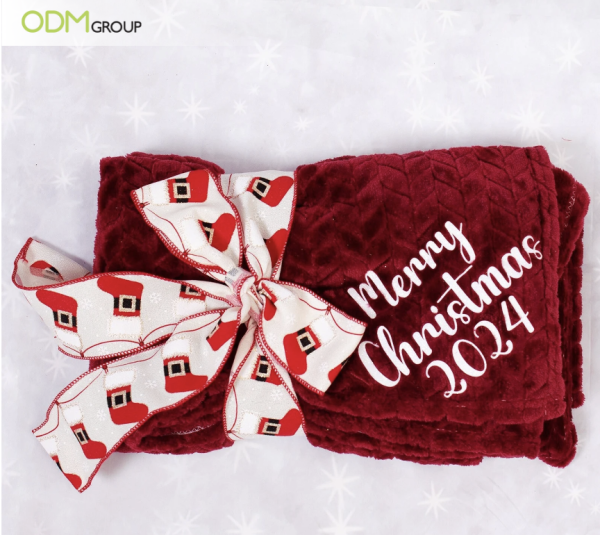 Cozy Christmas blanket with 'Merry Christmas 2024' and festive ribbon.
